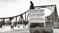 Schwarzweiß-Bild: Fußgänger gehen über Brücke, davor ein Schild mit der Aufschrift: "Sie verlassen den amerikanischen Sektor".