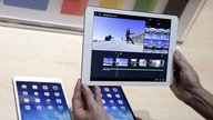 Das Bild zeigt ein Paar Hände und drei mobile Endgeräte der Firma Apfel