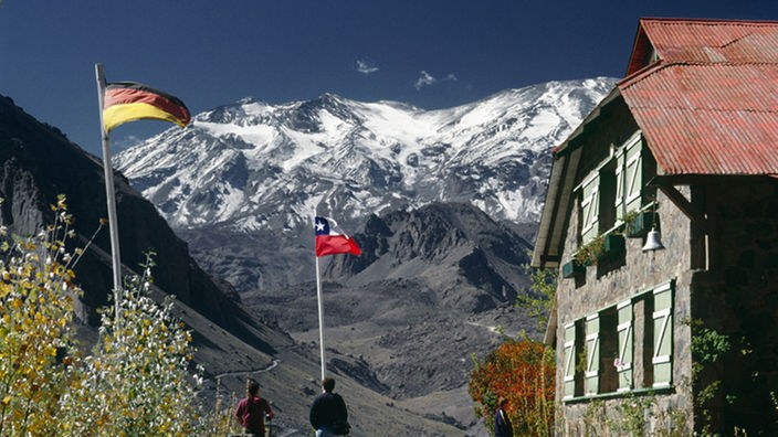 Die deutsche und chilenische Flagge, im Hintergrund Berge.