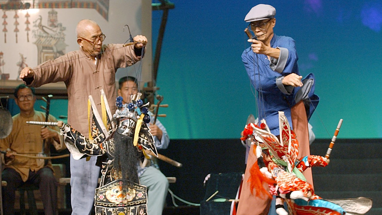 Zwei chinesische Puppenspieler mit Marionetten.