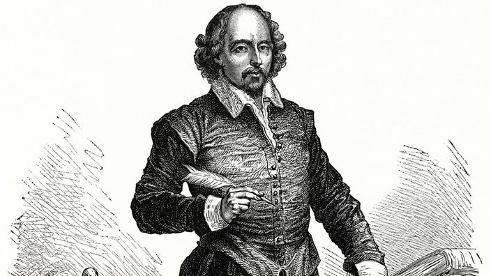 Der englische Dichter William Shakespeare steht mit Feder in der Hand neben einem Tisch