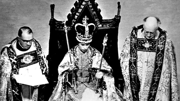 Königin Elisabeth II. von England sitzt bei ihrer Krönung mit Krone und Zeptern auf einem Thron 