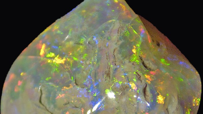 Ein weißer Opal schimmert in allen Regenbogenfarben