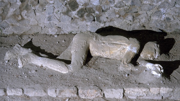 Auf einem Bürgersteig in Pompeji liegt der Gipsabdruck einer Leiche | Bildquelle: AKG/Tristan Lafranchis Auf einem Bürgersteig in Pompeji liegt der Gipsabdruck einer Leiche