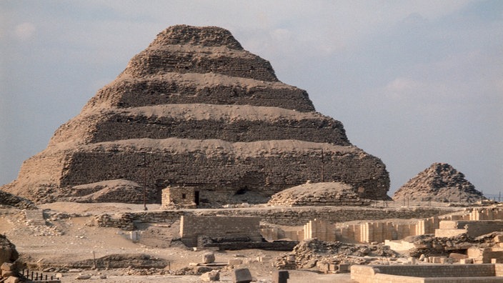 Blick auf eine Pyramide in Stufenform. Vor der Pyramide sind Grabungsfelder zu sehen. | Bildquelle: WDR / dpa Blick auf eine Pyramide in Stufenform. Vor der Pyramide sind Grabungsfelder zu sehen.
