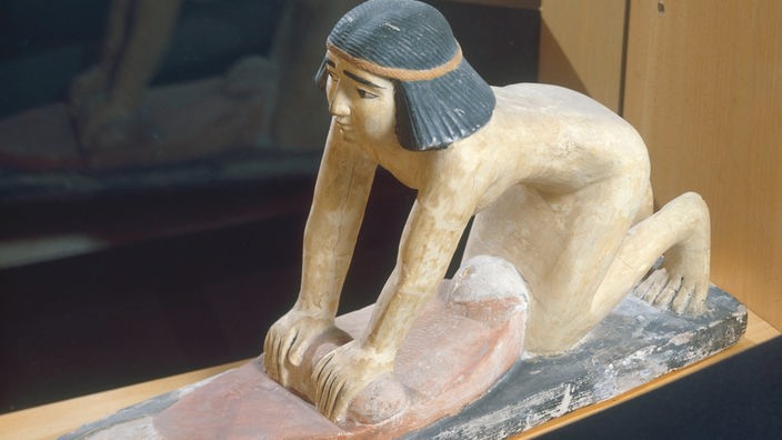 Ägyptische Skulptur, die eine kniende Frau beim Kornmahlen zeigt