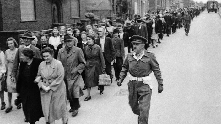 Britische Soldaten führen Bewohner der Stadt Burgsteinfurt 1945 zum Kino geführt, um einen Film mit Beweismaterial über die Grausamkeiten in den Konzentrationslagern Bergen-Belsen und Buchenwald anzusehen | Bildquelle: picture alliance / ASSOCIATED PRESS Britische Soldaten führen Bewohner der Stadt Burgsteinfurt 1945 zum Kino geführt, um einen Film mit Beweismaterial über die Grausamkeiten in den Konzentrationslagern Bergen-Belsen und Buchenwald anzusehen