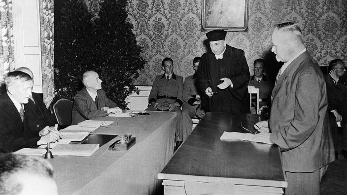 Ein Beklagter steht mit seinem Verteidiger vor einer Entnazifizierungs-Spruchkammer | Bildquelle: picture alliance / dpa Ein Beklagter steht mit seinem Verteidiger vor einer Entnazifizierungs-Spruchkammer