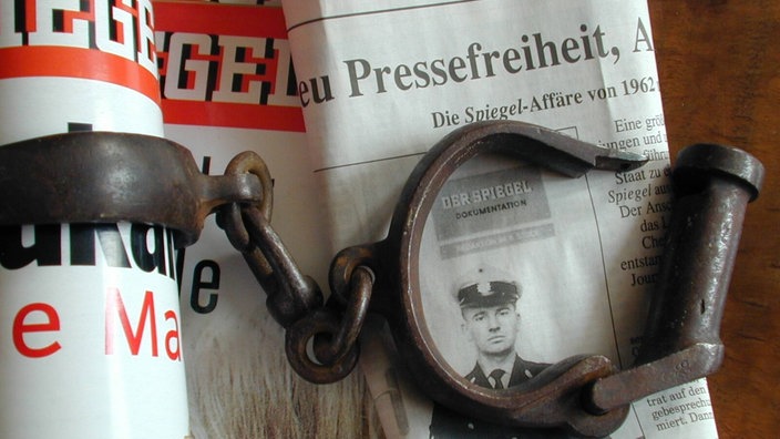 Eine Handschelle liegt auf einer Ausgabe der Zeitschrift "Der Spiegel" und einer Zeitung, auf der das Wort "Pressefreiheit" zu sehen ist | Bildquelle: imago stock&people Eine Handschelle liegt auf einer Ausgabe der Zeitschrift "Der Spiegel" und einer Zeitung, auf der das Wort "Pressefreiheit" zu sehen ist