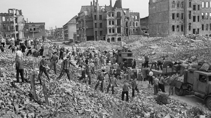 Menschen stehen in einer Stadt in Trümmern und tragen Ziegelsteine, September 1945 | Bildquelle: picture alliance / ZB Menschen stehen in einer Stadt in Trümmern und tragen Ziegelsteine, September 1945