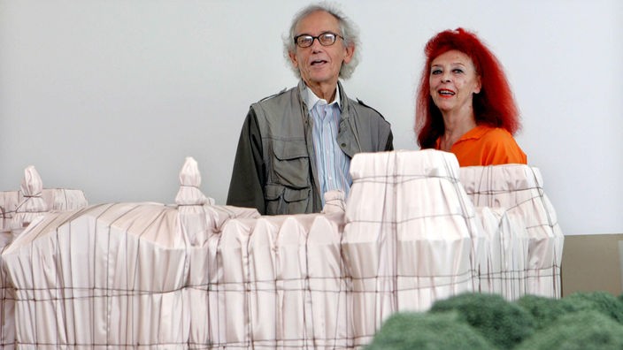 Das Ehepaar Christo steht hinter einem Modell des verhüllten Reichstages.
