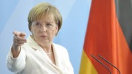 Bundeskanzlerin Angela Merkel steht neben Deutschlandfahne
