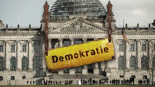 Vergilbtes Bild des Reichstagsgebäude an dem an rostigen Ketten ein Schild mit der Aufschrift "Demokratie" hängt.