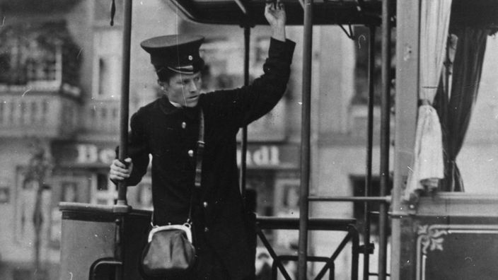 schwarz-weiss Bild einer Straßenbahnschaffnerin auf einem Zug