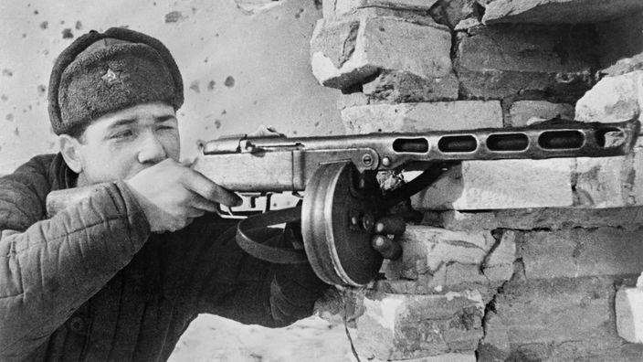 Schwarzweißaufnahme: Ein russischer Soldat im Ersten Weltkrieg mit einem Maschinengewehr im Anschlag.