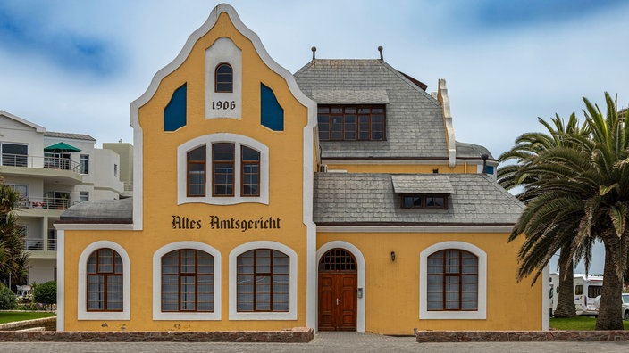 Fassade des alten deutschen Landgerichtsgebäudes in Swakopmund, Namibia | Bildquelle: picture alliance / CHROMORANGE Fassade des alten deutschen Landgerichtsgebäudes in Swakopmund, Namibia