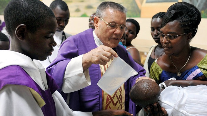 Ein Geistlicher tauft in Afrika ein Kind | Bildquelle: imago/Passage Ein Geistlicher tauft in Afrika ein Kind