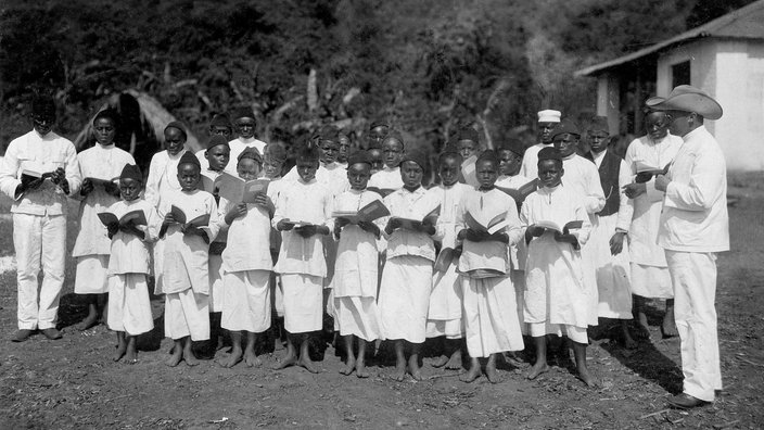 Ein christlicher Missionar singt mit afrikanischen Kindern Lieder