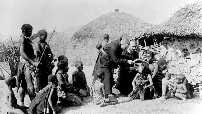 Missionare taufen Kinder in einem afrikanischen Dorf | Bildquelle: picture alliance / ullstein bild (Haeckel Archiv) Missionare taufen Kinder in einem afrikanischen Dorf