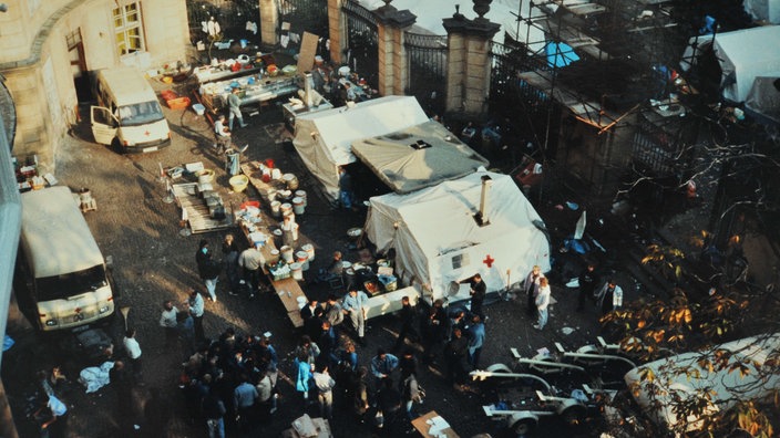 DDR-Flüchtlinge stehen vor Versorgungs-Zelten des DRK im Innenhof der deutschen Botschaft in Prag | Bildquelle: picture alliance DDR-Flüchtlinge stehen vor Versorgungs-Zelten des DRK im Innenhof der deutschen Botschaft in Prag