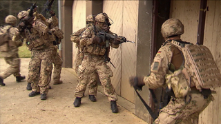 Soldaten mit Gewehren vor einer Tür.