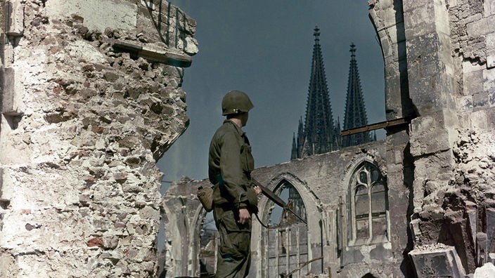 Soldat in Kölner Ruinen, im Hintergrund der Dom