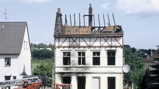 Das ausgebrannte Haus der Gastarbeiterfamilie. Der Dachstuhl ist größtenteils zerstört, die Fenster sind herausgebrochen.