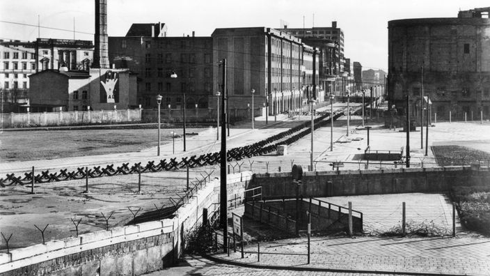 Schwarzweiß-Foto mit Blick auf den Potsdamer Platz in Berlin. Im Vordergrund verläuft die Mauer.