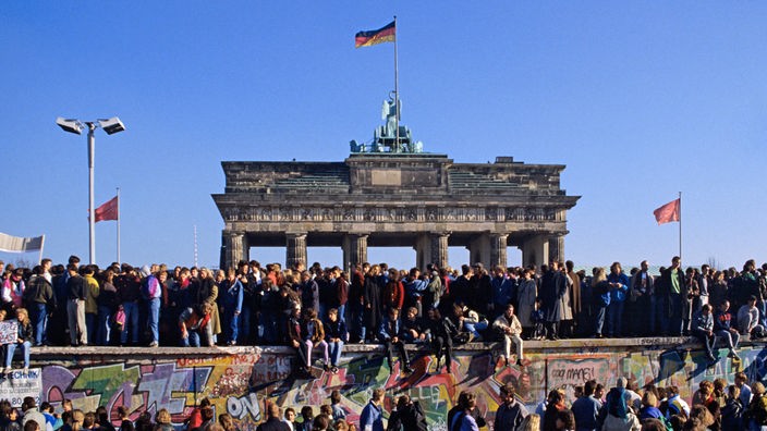 Feiernde Menschen auf der Berliner Mauer vor dem Brandenburger Tor.
