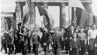 Schwarzweiß-Foto einer Demonstration vor dem Brandenburger Tor. Einige Menschen schwenken die deutsche Fahne.