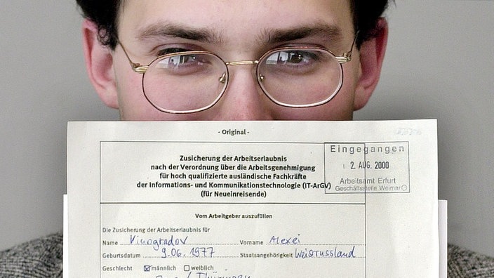 Mann, der seine Arbeitserlaubnis vor sich hält. | Bildquelle: WDR/AP Mann, der seine Arbeitserlaubnis vor sich hält.