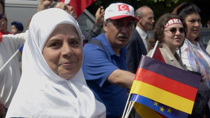Türkische Fraue mit deutscher Papierfahne in der Hand