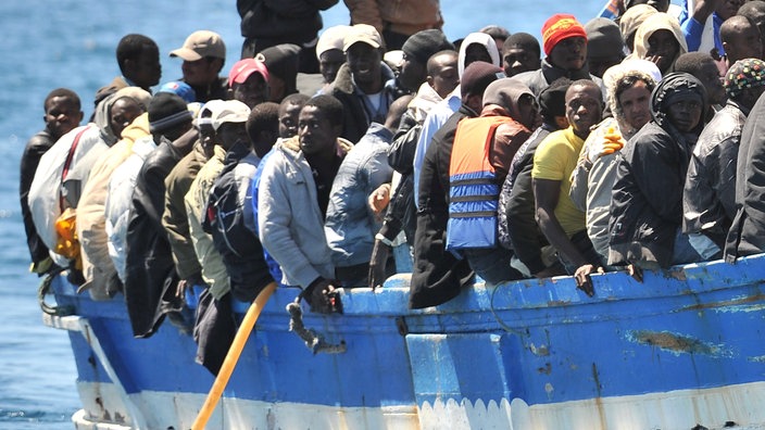 Männer auf einem übervollen Flüchtlingsboot | Bildquelle: Ettore Ferrari Männer auf einem übervollen Flüchtlingsboot