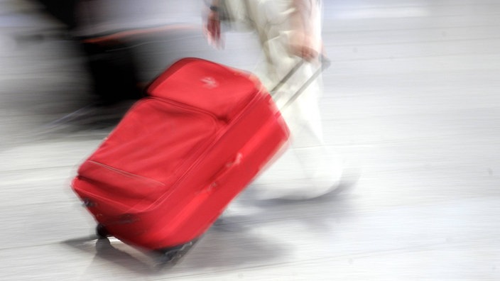 Person zieht einen roten Rollkoffer | Bildquelle: imago Ralph Peters Person zieht einen roten Rollkoffer