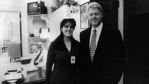Monica Lewinsky und Bill Clinton stehen auf dem Schwarzweiß-Foto nebeneinander und lächeln in die Kamera.