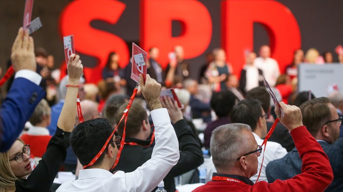 Delegierte bei einem SPD-Bundesparteitag halten ihre Stimmkarten hoch.