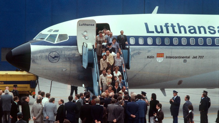 Viele befreite Geiseln drängen sich die Treppe der blau-weißen Lufthansa-Maschine hinunter auf die Landebahn in Frankfurt am Main. | Bildquelle: dpa Viele befreite Geiseln drängen sich die Treppe der blau-weißen Lufthansa-Maschine hinunter auf die Landebahn in Frankfurt am Main.