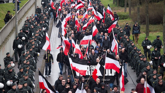 Demonstrationszug mit schwarz-weiß-roten Fahnen, flankiert von Polizeibeamten. | Bildquelle: dpa/Marius Becker Demonstrationszug mit schwarz-weiß-roten Fahnen, flankiert von Polizeibeamten.