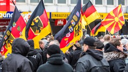Demonstration mit schwarz gekleideten Trägern von Fahnen mit deutschen Symbolen.