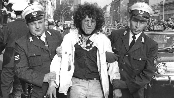 Schwarzweiß-Foto: Der Kommunarde Rainer Langhans wird nach seiner Festnahme von zwei Polizeibeamten abgeführt.