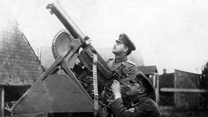 Schwarzweiß-Foto: Zwei Soldaten an einem Maschinengewehr.