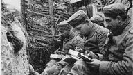 Deutsche Soldaten im Schützengraben beim Schreiben von Grußkarten