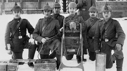 Schwarz-weißes Gruppenbild deutscher Maschinengewehrschützen vor einer Kaserne in Schweidnitz, Schlesien, von 1917. Die Männer tragen Uniform und Helm, in ihrer Mitte steht ein Maschinengewehr. | Bildquelle: akg Schwarz-weißes Gruppenbild deutscher Maschinengewehrschützen vor einer Kaserne in Schweidnitz, Schlesien, von 1917. Die Männer tragen Uniform und Helm, in ihrer Mitte steht ein Maschinengewehr.
