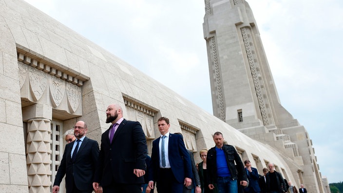 Eine Gruppe Menschen geht am Eingang des Beinhauses der Kriegs-Gedenkstätte Douaumont vorbei | Bildquelle: AFP / JEAN CHRISTOPHE VERHAEGEN Eine Gruppe Menschen geht am Eingang des Beinhauses der Kriegs-Gedenkstätte Douaumont vorbei