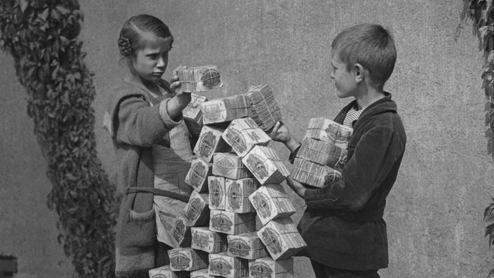 Kinder spielen mit Bündeln von Geldscheinen.