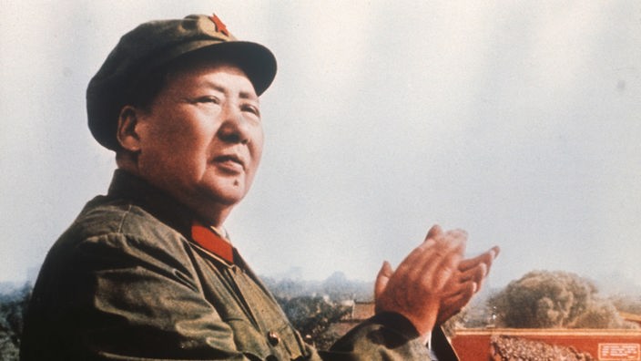 Mao 1969 während der Feiern zum zwanzigjährigen Bestehen der Volksrepublik China. Er trägt eine Uniform. Auf der Mütze prangt ein roter Stern. Er klatscht in die Hände.