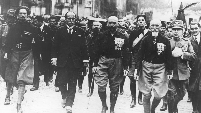 Schwrzweiß-Bild: Mehrer Männer marschieren nebeneinander her