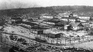 Zeichnung des Gulag Workuta: Ein paar Häuser, die in der Einöde stehen, sind von Stacheldrahtzäunen umgeben.