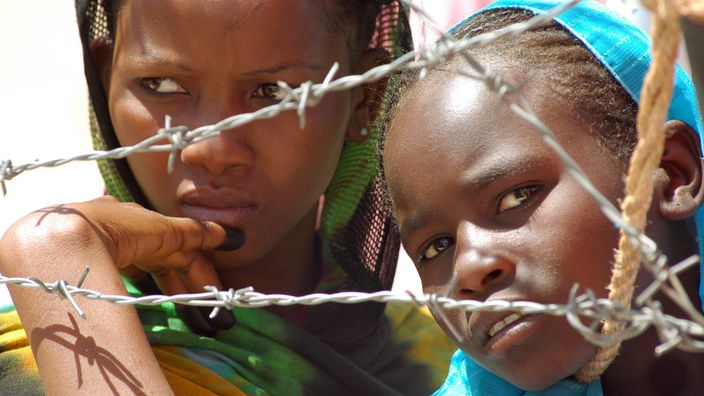 Zwei Mädchen hinter Stacheldraht in einem Flüchtlingslager im sudanesischen Darfur.