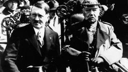 Reichspräsident Paul von Hindenburg sitzt neben Adolf Hitler.